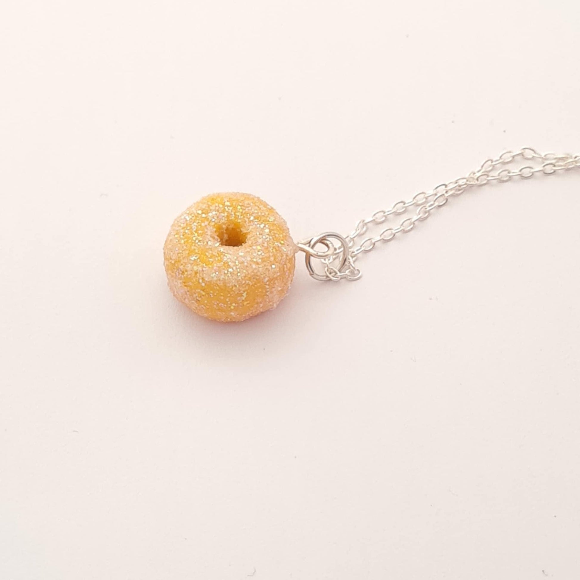 Donut-shaped pendant on a silver chain against a white background