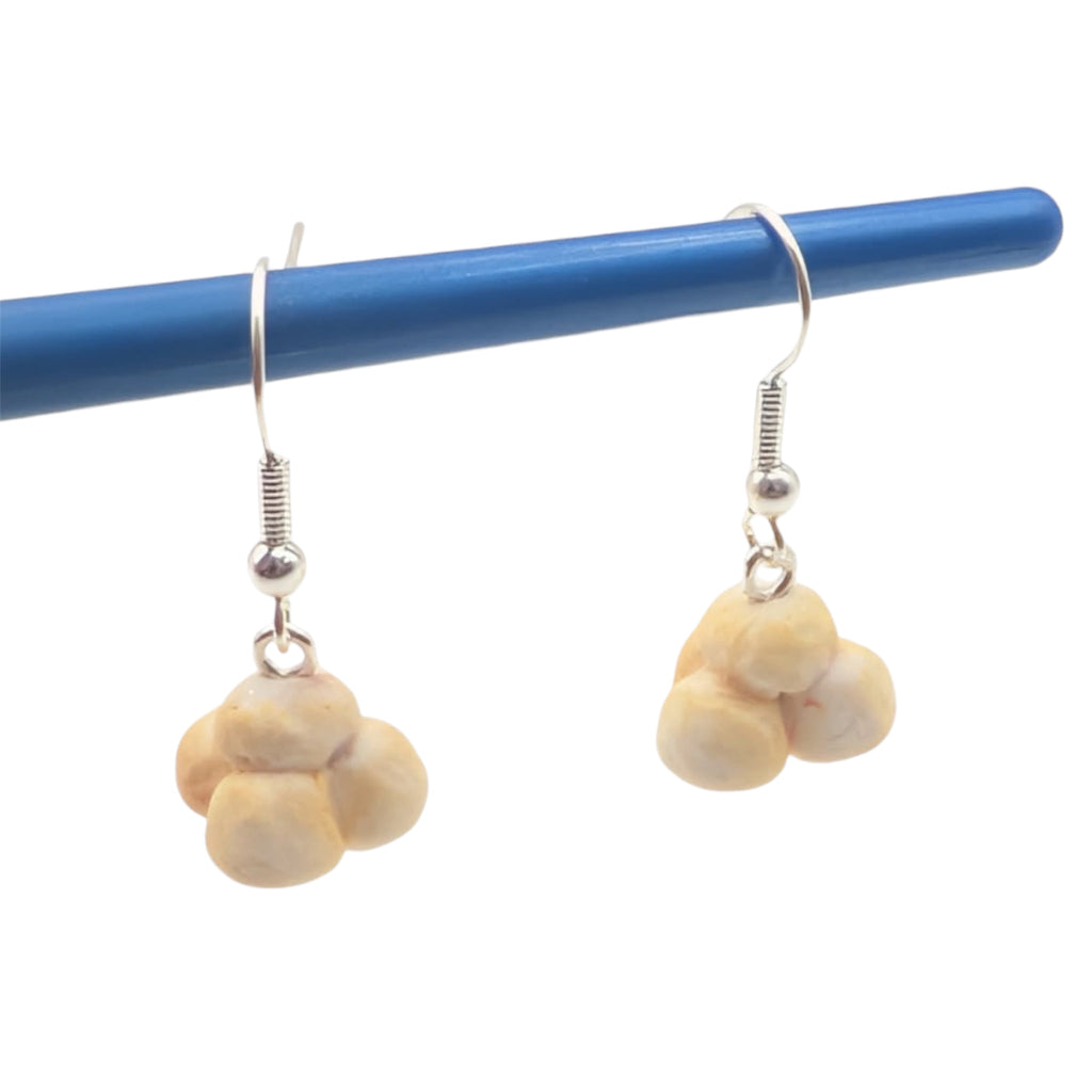 Handmade popcorn earrings hanging from a blue display, showcasing their unique dangle design.