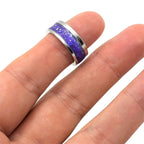 Ring with purple and silver design on a finger against a white background