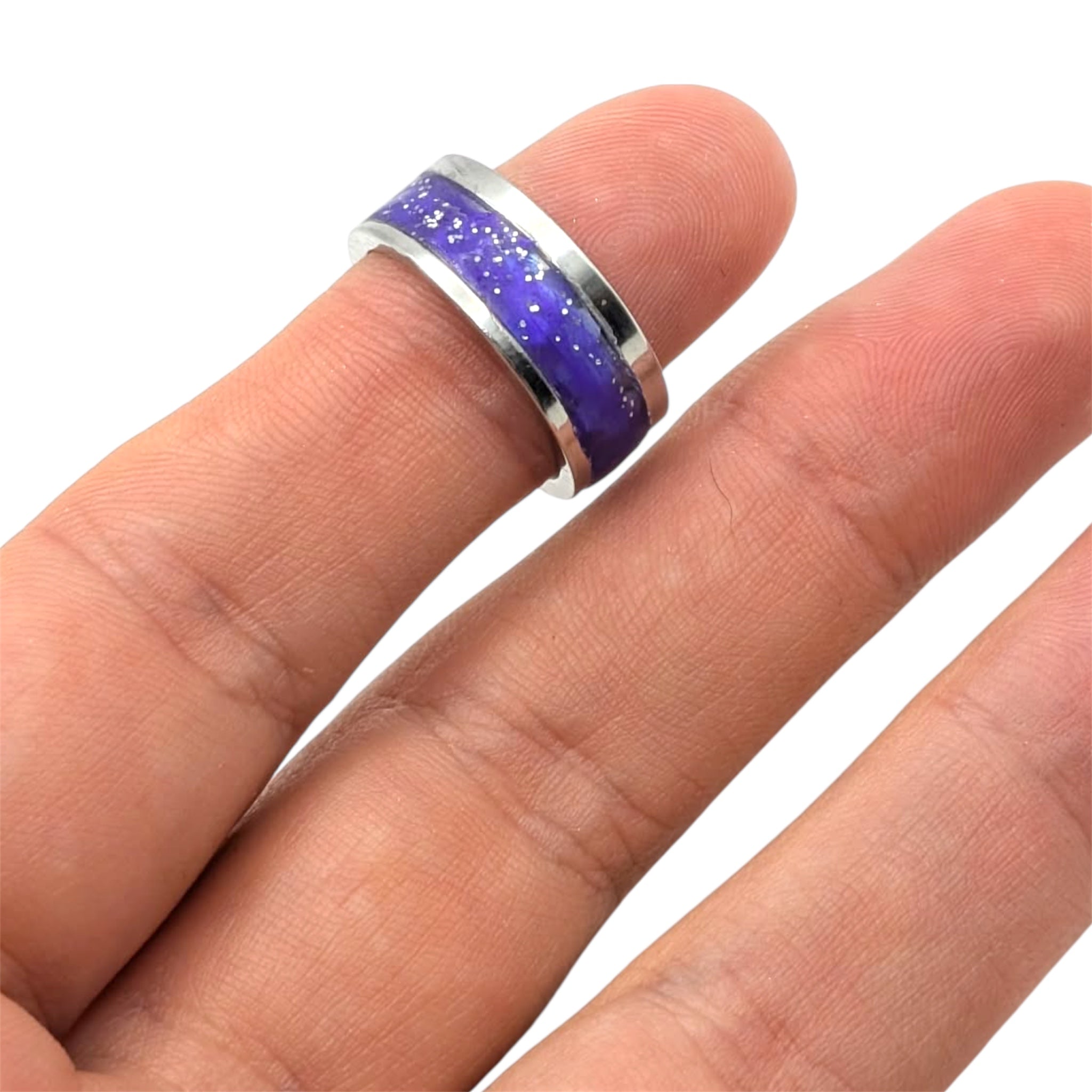 Ring with purple and silver design on a finger against a white background