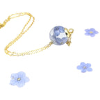 Jewelry set with blue floral pendants and gold chain on a white background