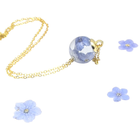 Jewelry set with blue floral pendants and gold chain on a white background