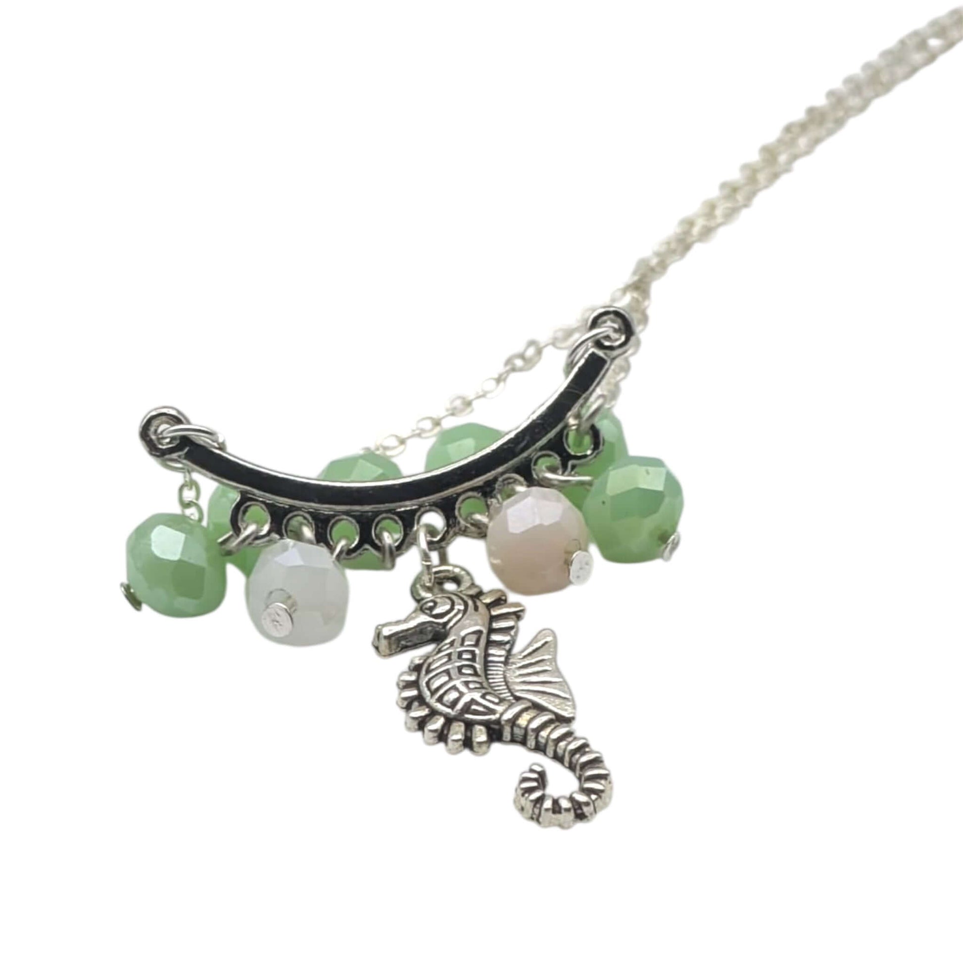 Handmade green and pink crystal seahorse necklace on white background 