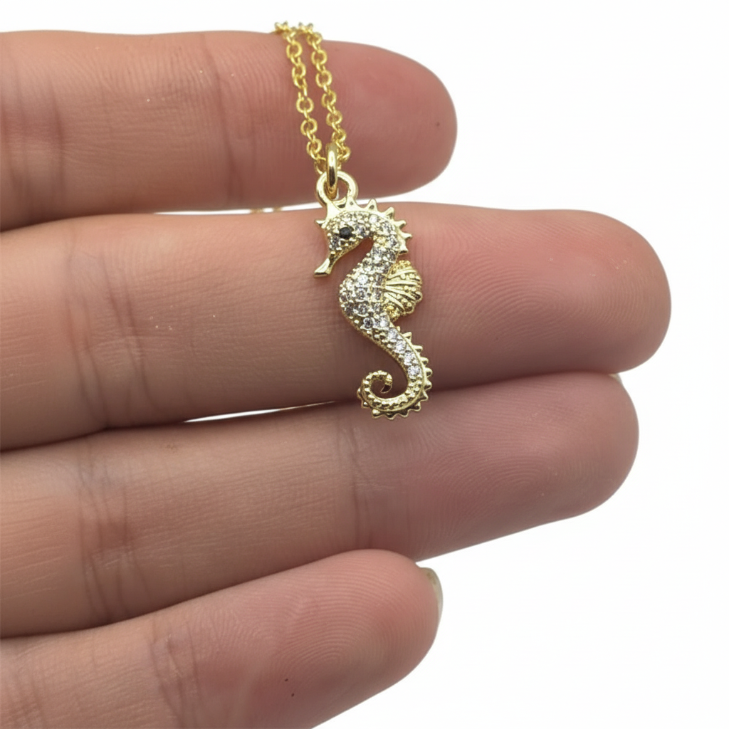 Gold-plated seahorse necklace with zirconia accents held in hand showing textured pendant detail