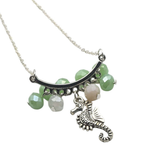 Silver pink and green seahorse necklace on white background 
