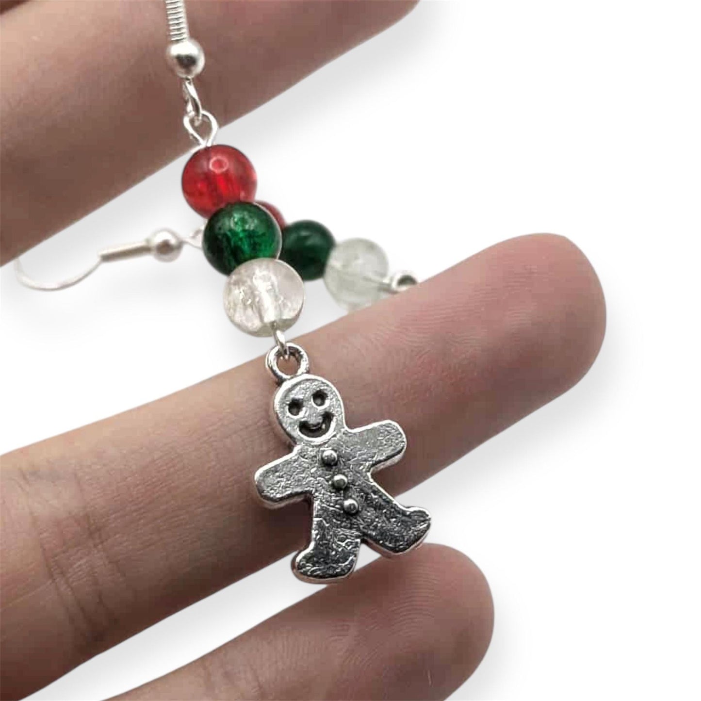 Gingerbread man earring with colorful beads on a finger against a white background
