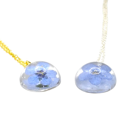 Necklace with round pendants featuring dried blue flowers on a white background