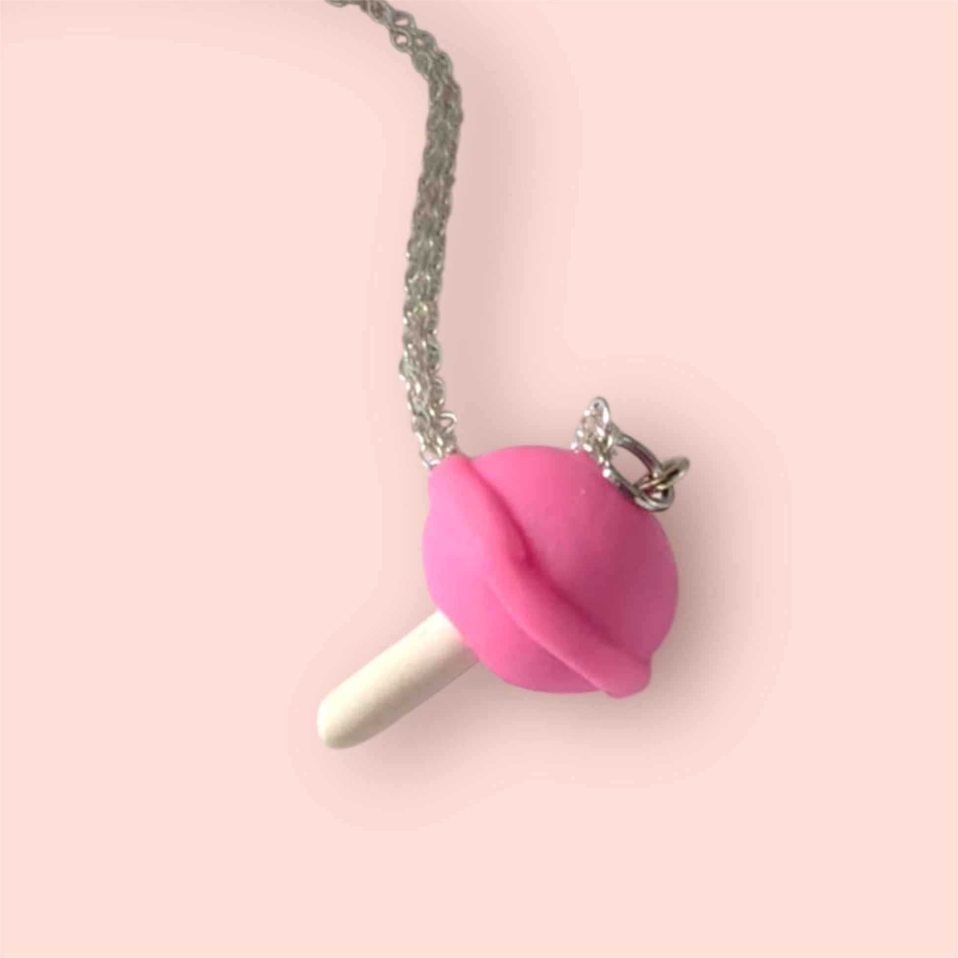Necklace with a pink lollipop pendant on a light pink background