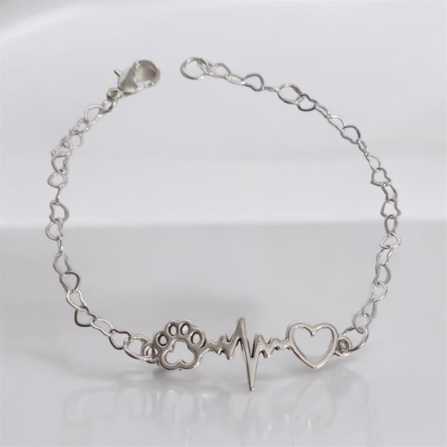 Paw bracelet featuring a paw print, heartbeat, and heart charm in silver, perfect for dog lovers.
