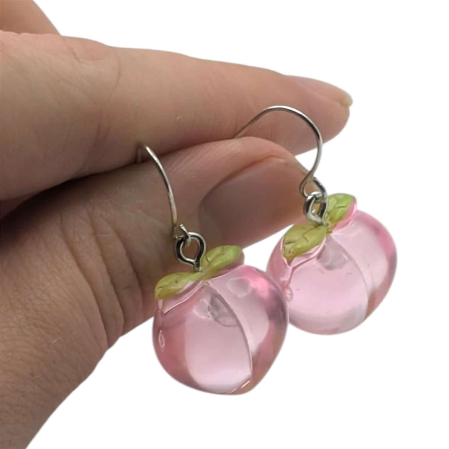 Peach earrings held in hand on white background 