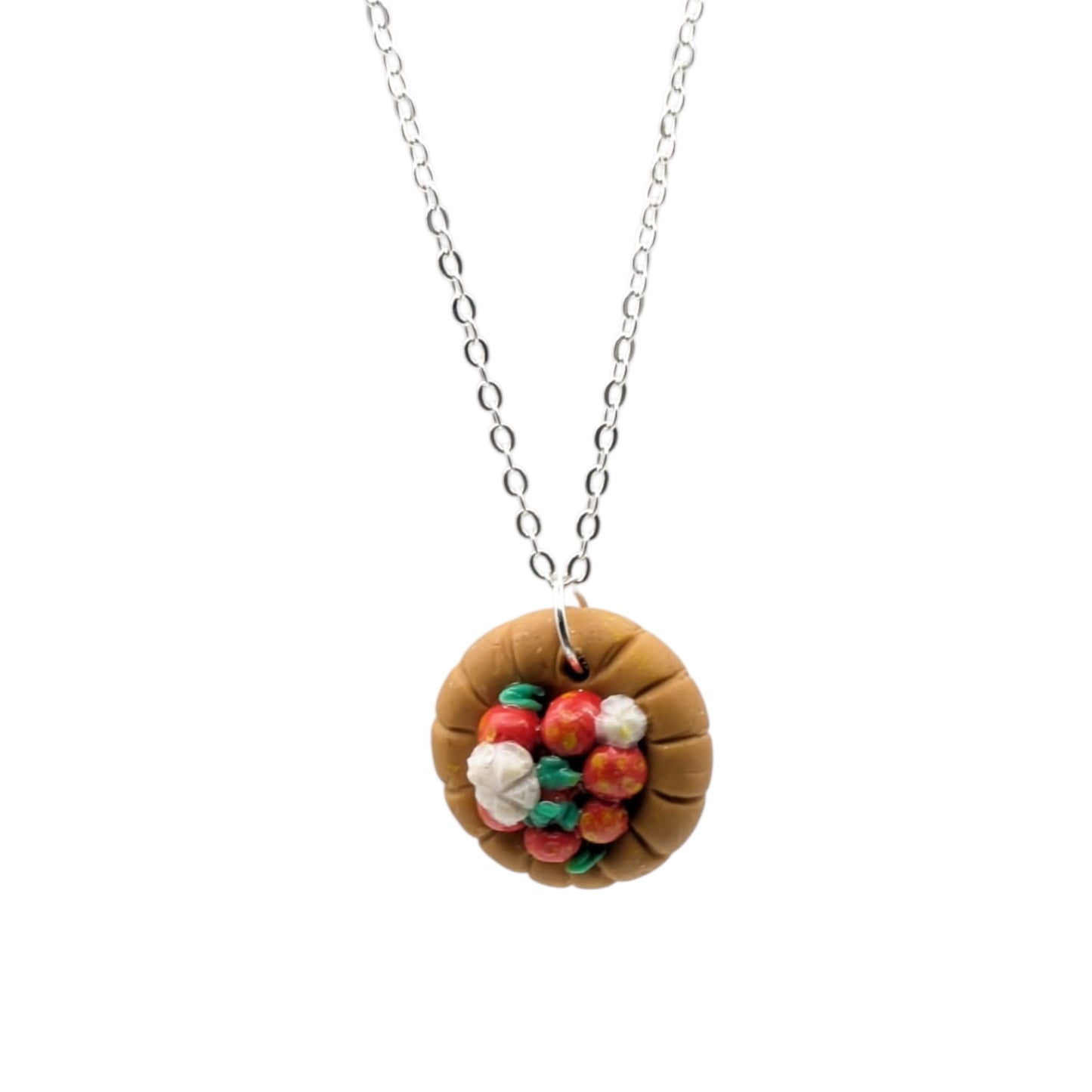 Strawberry tart necklace with whipped cream and green leaves on a white background 