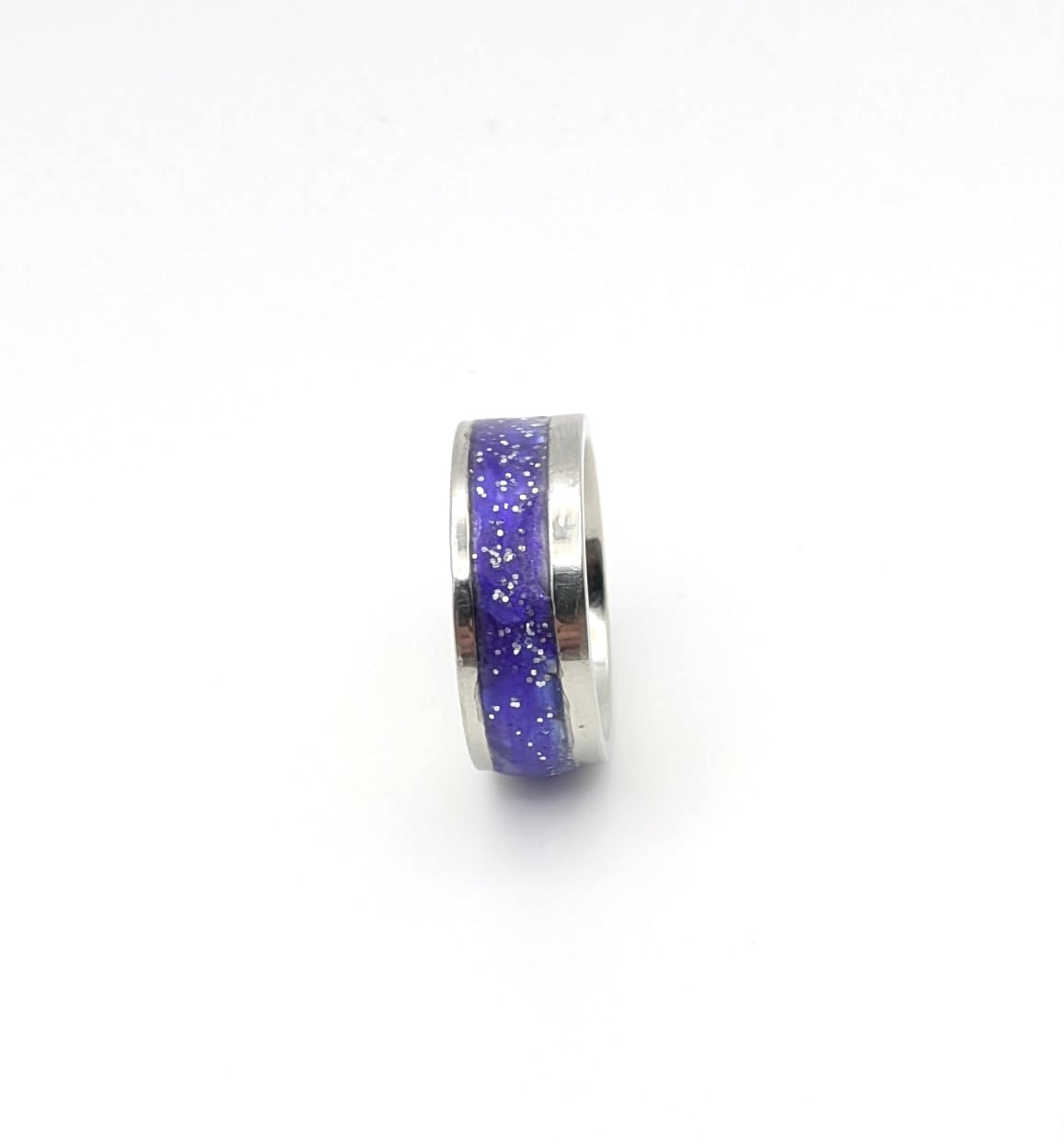 Silver ring with purple glittery band on a white background