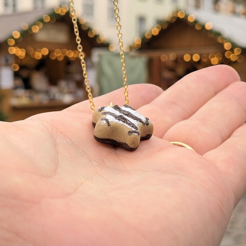 Miniature lebkuchen star cookie necklace resting on a palm for scale