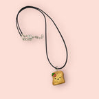Necklace with a cute bread charm on a pink background