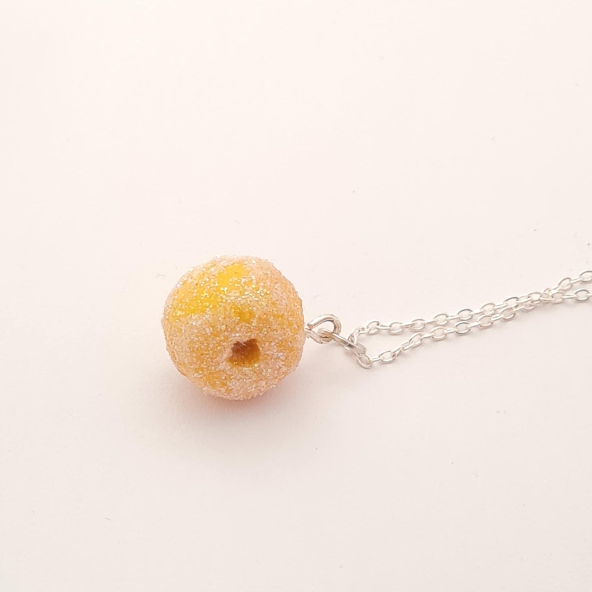 Necklace with a sugar donut pendant on a light pink background