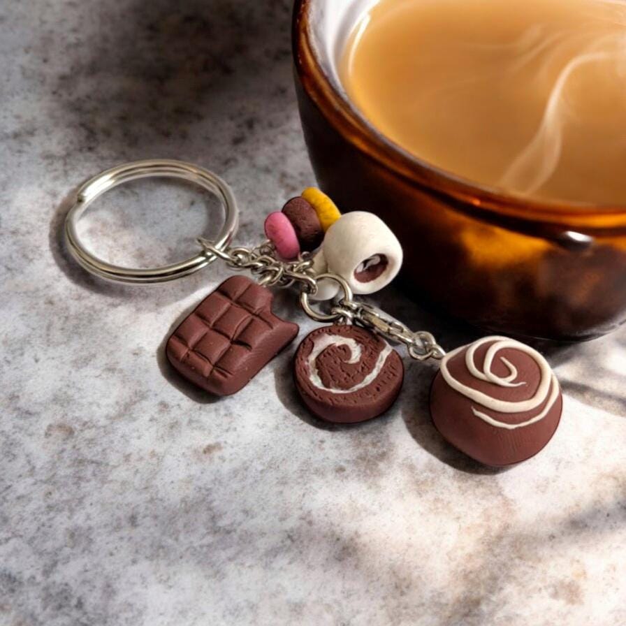 Keychain with chocolate-themed charms next to a cup of coffee on a marble surface