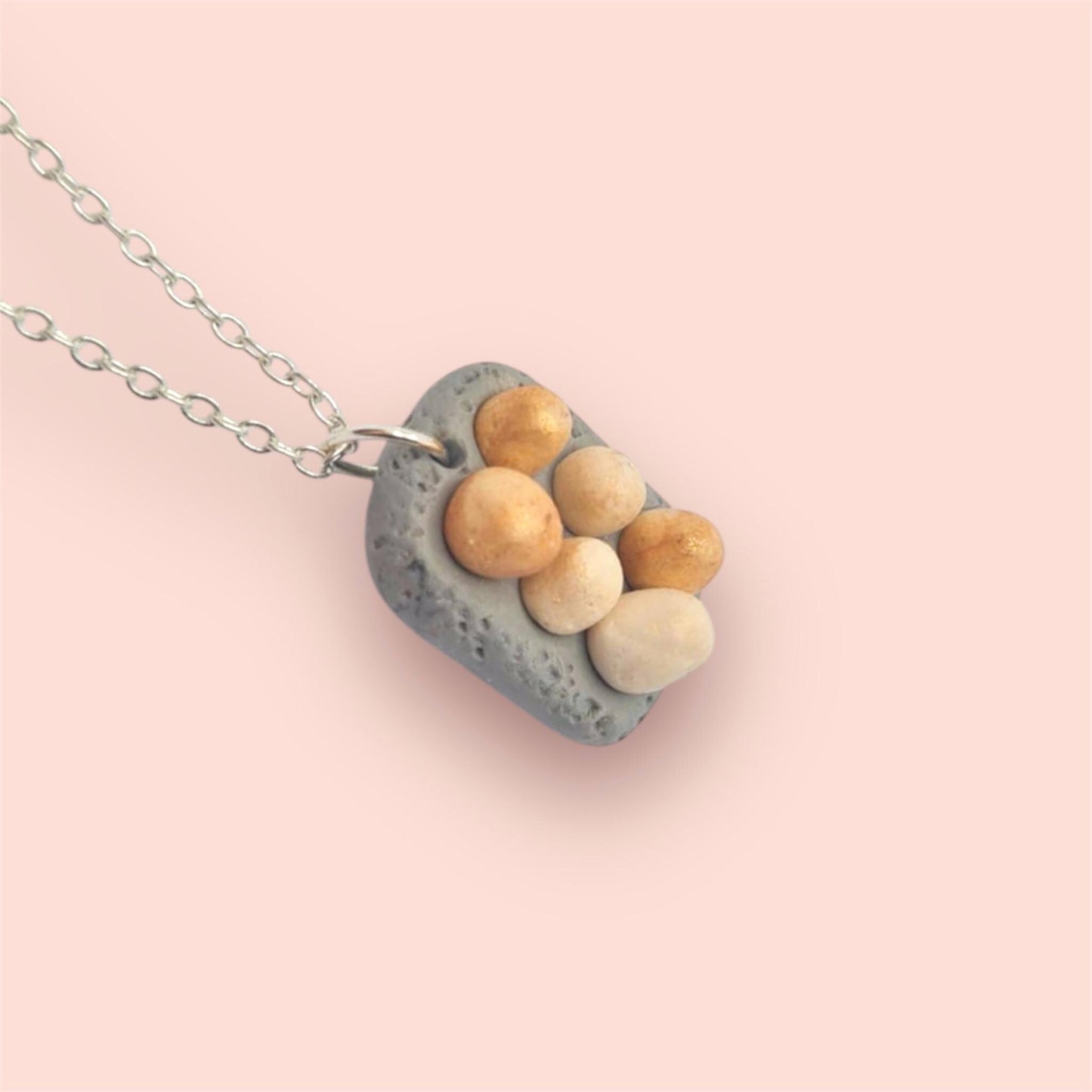 Necklace with a pendant featuring eggs on a pink background