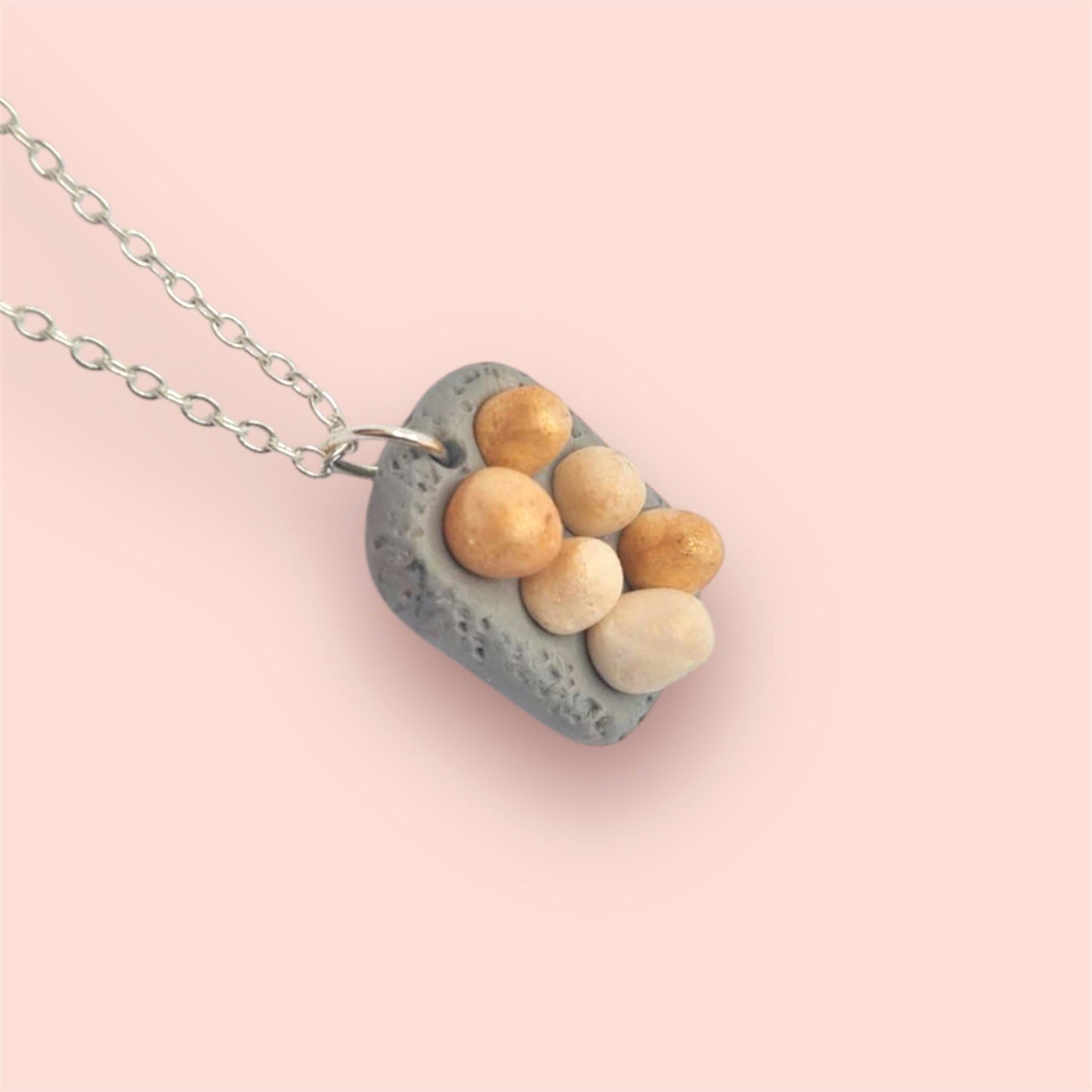 Necklace with a pendant featuring eggs on a pink background