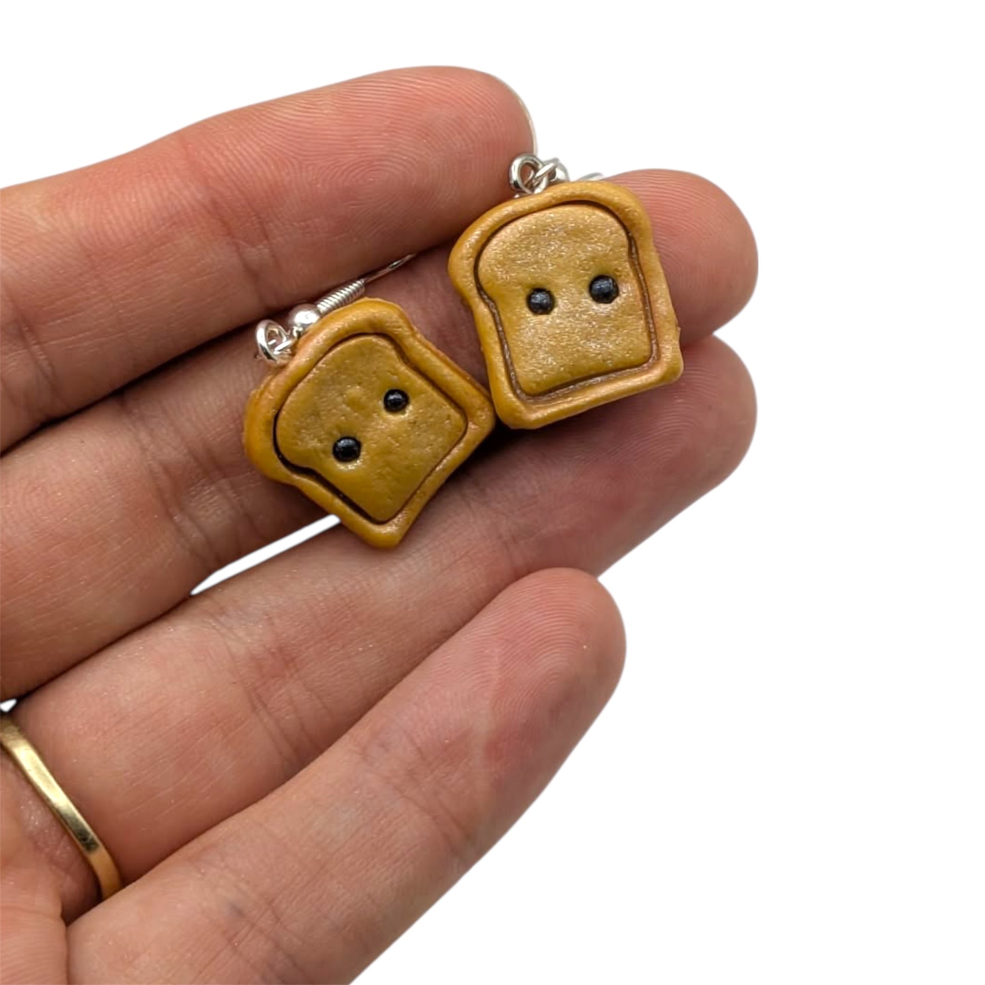 Cute handmade polymer clay toast earrings - kawaii breakfast food jewellery on silver hooks held in hand on white background