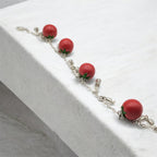 Bracelet with red tomato-shaped polymer clay charms on a white surface