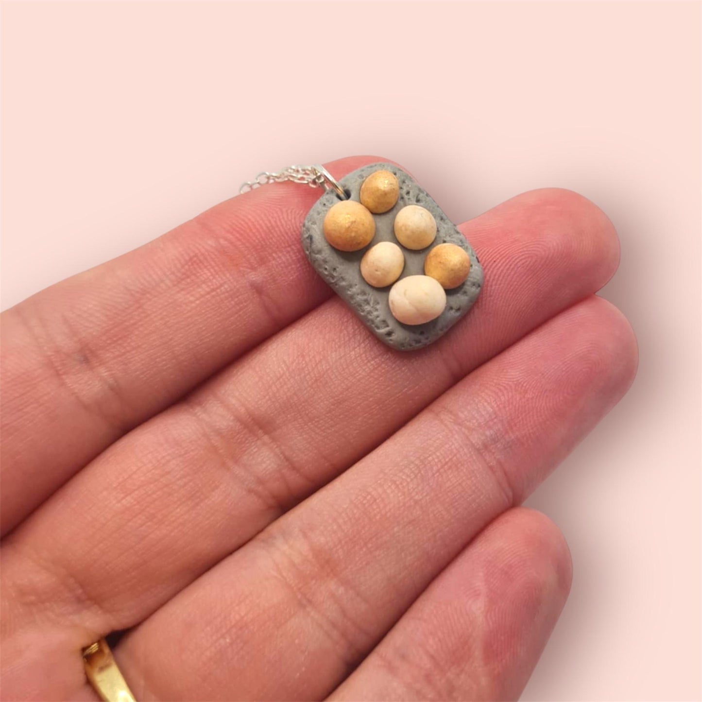 Half a dozen eggs in a tray miniature food jewellery held on hand against a. Light pink background 