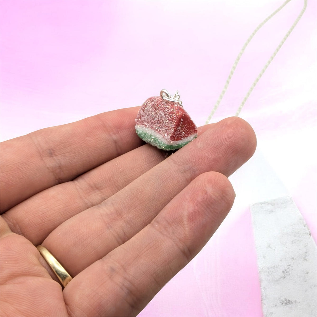 Hand holding watermelon sweet necklace, sugary sweet pendant, miniature food gift 
