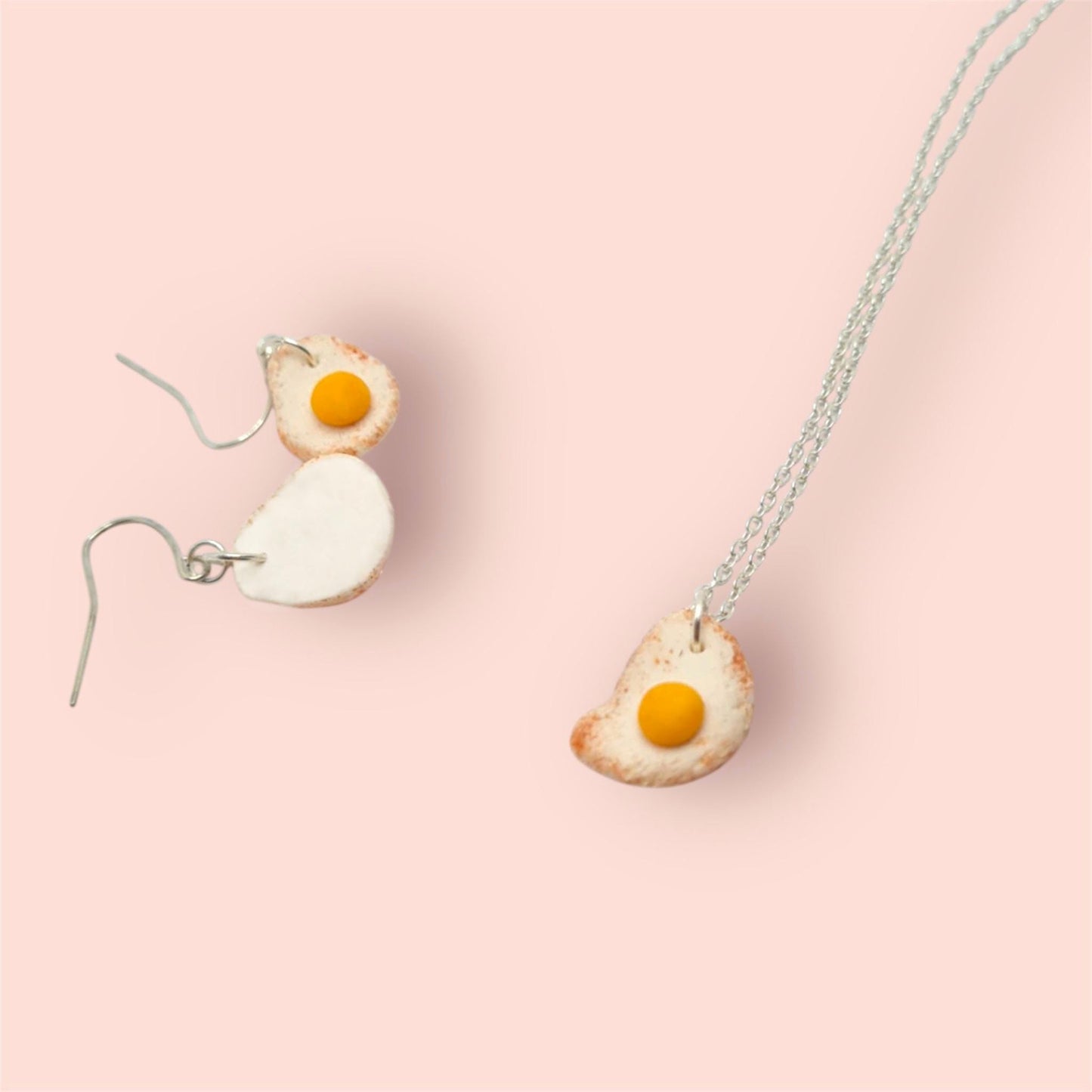 Fried egg-shaped earrings on a pink background