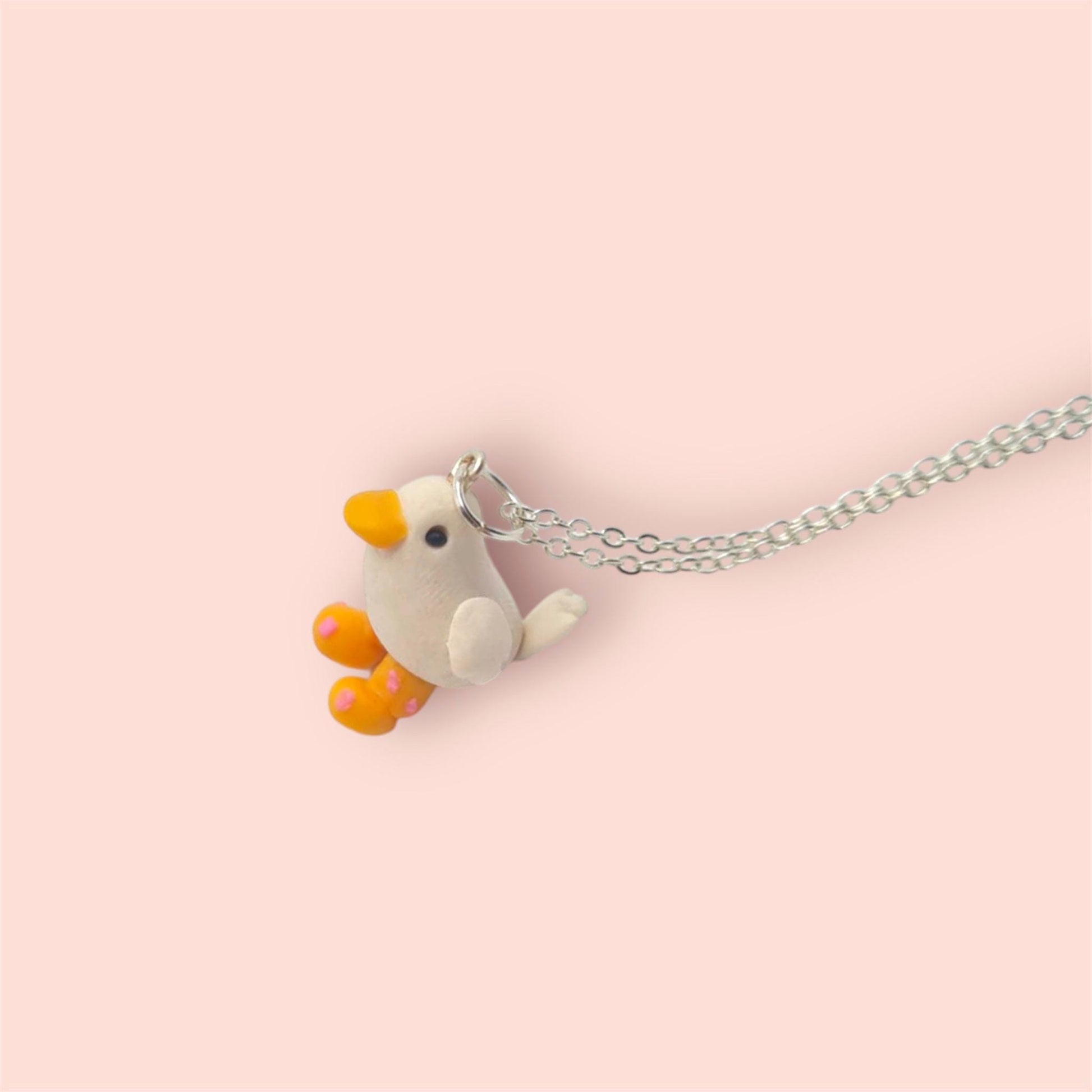 Necklace with a small bird-shaped pendant on a pink background